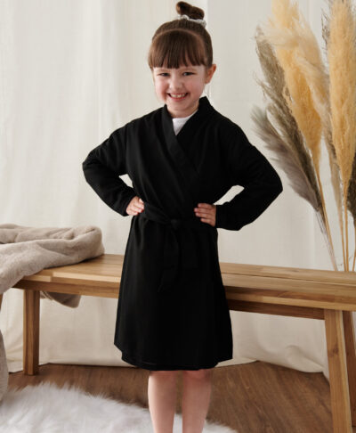 Smiling child wearing a black personalised cotton robe – perfect for flower girls, page boys, or junior bridesmaids on the wedding morning.