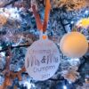 Personalised Christmas bauble reading “Our First Christmas As Mr & Mrs” with surname and year, hanging on a festive Christmas tree.
