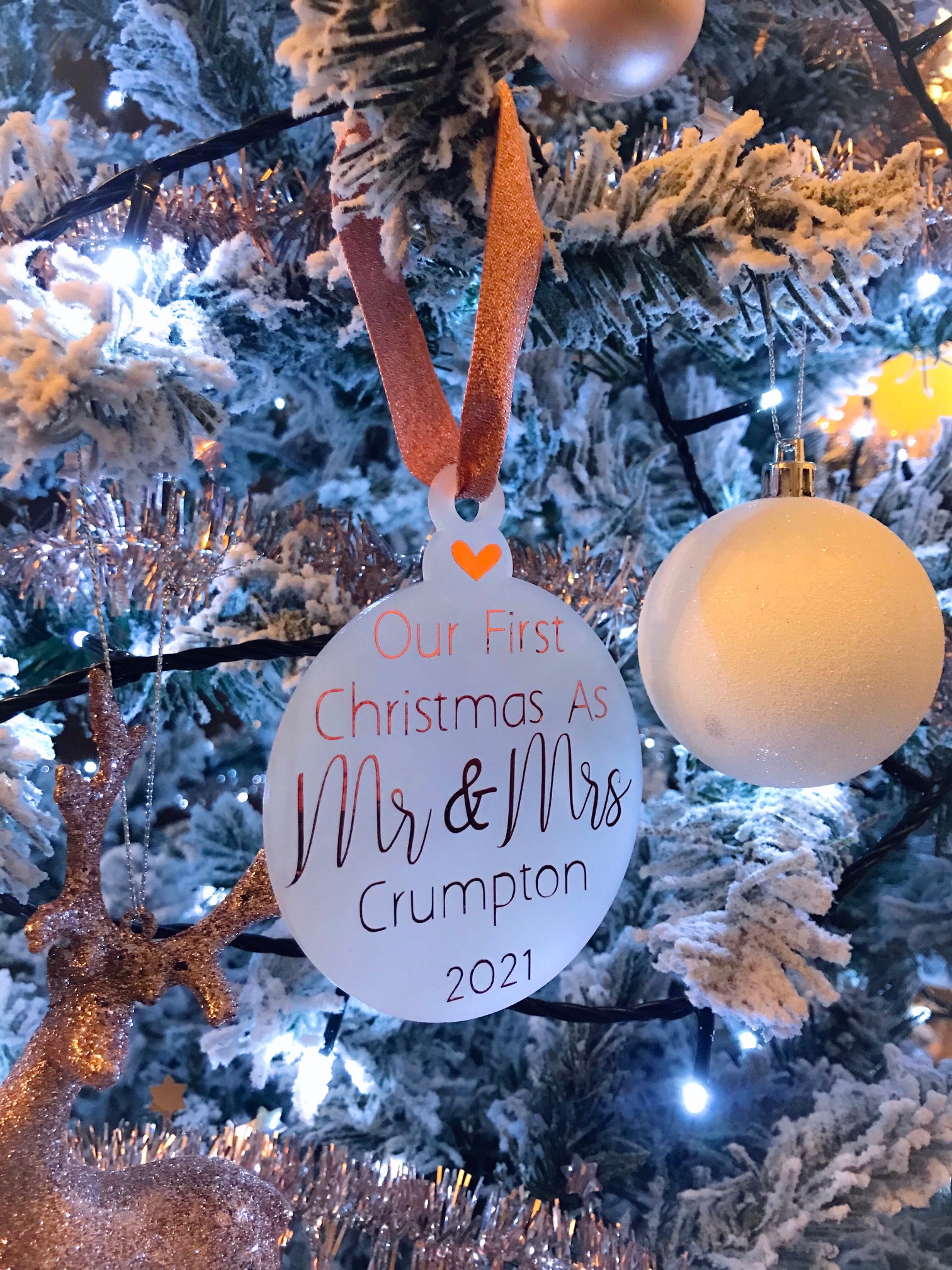 Personalised Christmas bauble reading “Our First Christmas As Mr & Mrs” with surname and year, hanging on a festive Christmas tree.